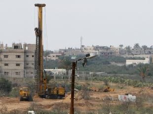 Photographed by: AFP Machinery on the Egyptian side of borders area work in building the separating area between...